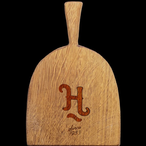Wooden serving paddle with an engraved 'H' logo and 'Since 1933' on a black background.