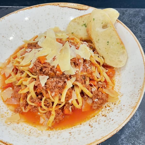 The Hub's American Bolognese, a pasta dish with meat sauce, parmesan, and garlic bread.