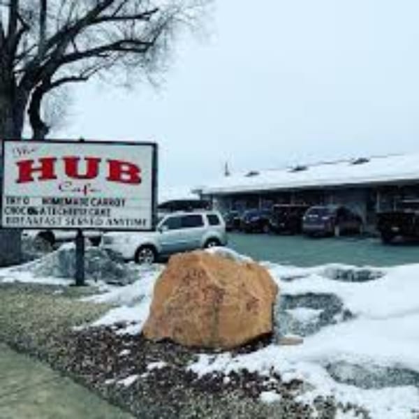 The Hub Cafe sign in front of the restaurant building and parking lot, with snow on the ground.