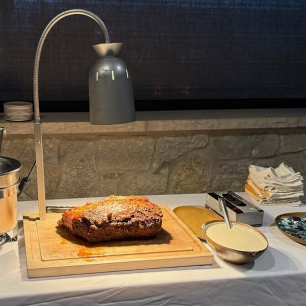 A large roasted prime rib on a wooden cutting board under a heat lamp at The Hub.