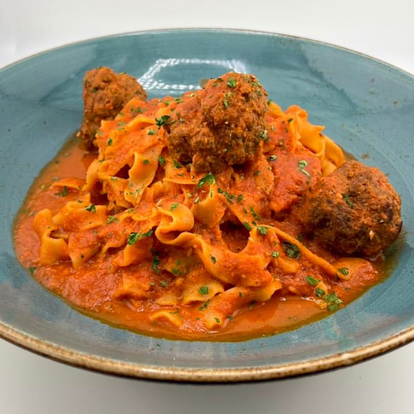 The Hub's American cuisine features pappardelle pasta with meatballs in a rich red sauce, garnished with parsley.